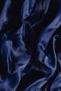 Close-up of dark blue silk fabric showcasing smooth texture and rich color, perfect for backgrounds.