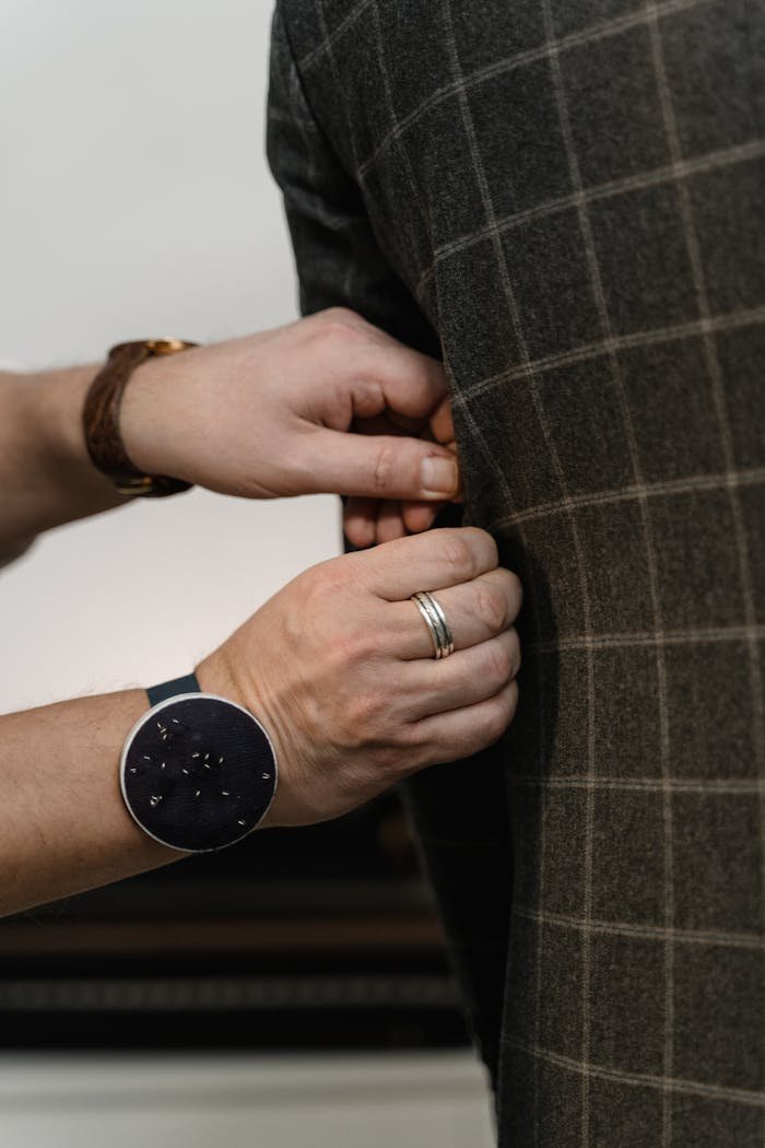 Close-up of a tailor's hands adjusting a suit jacket showing craftsmanship and detail.