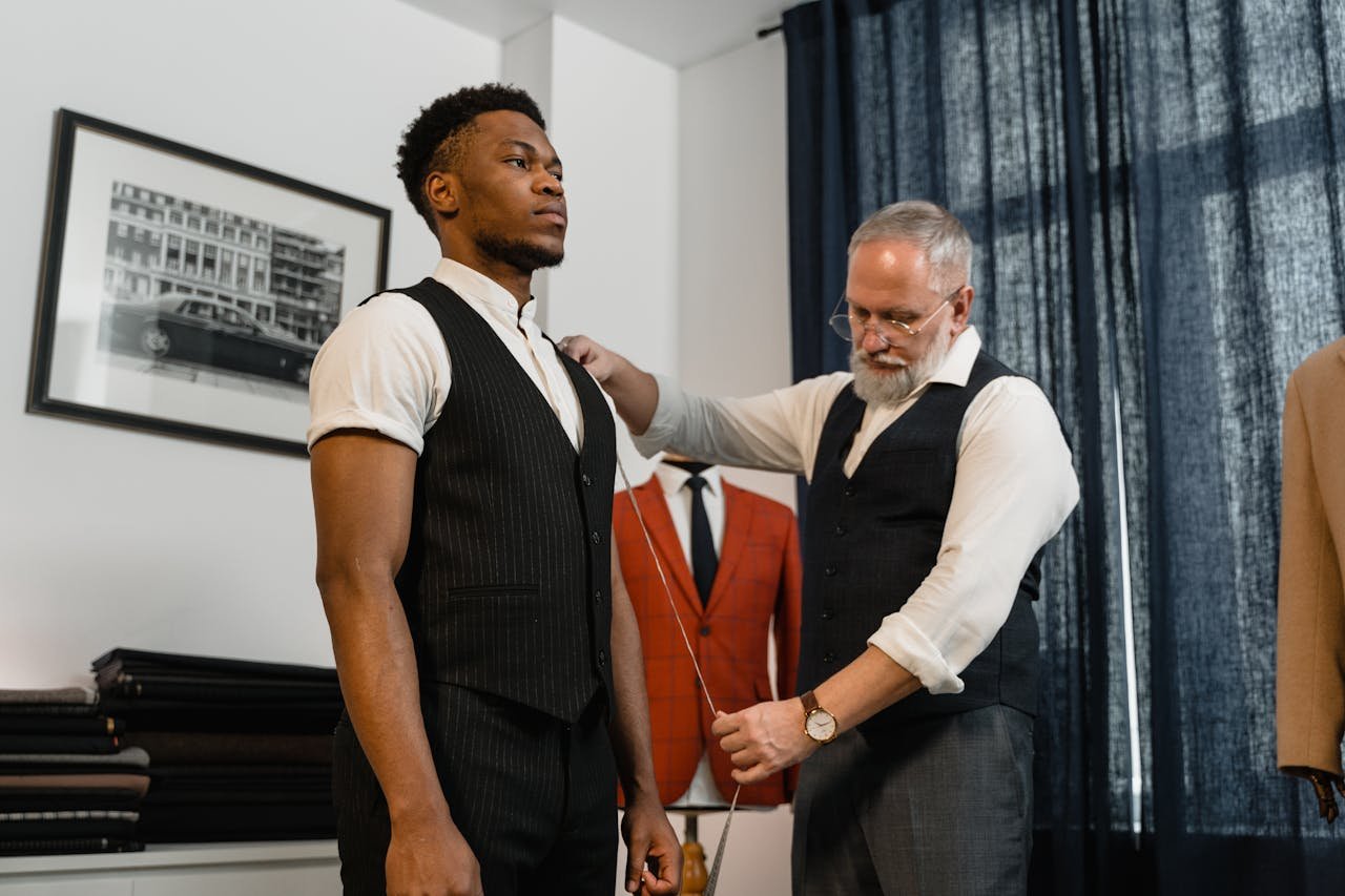 Tailor measures young client's suit in a stylish fashion studio. Professional attire and precision.